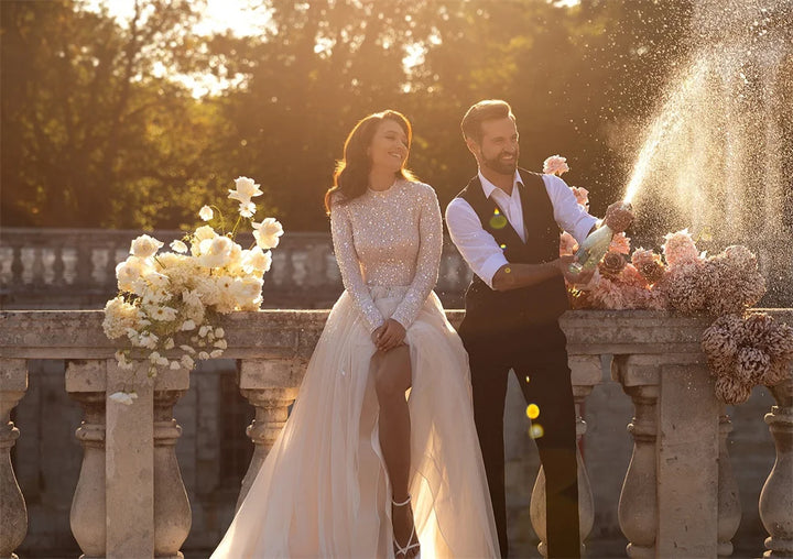 Couple celebrating with champagne by a fountain in a park setting
