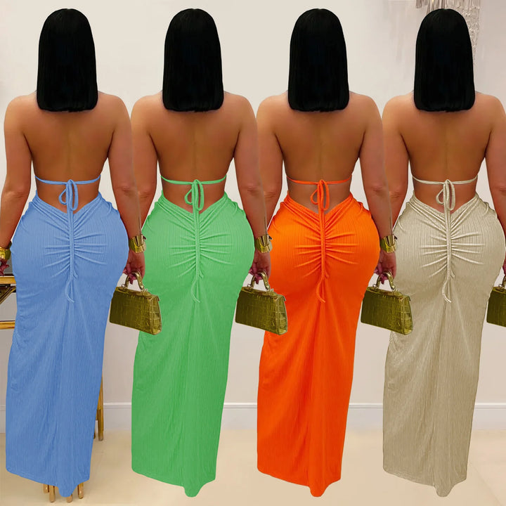 Four women wearing colorful backless dresses holding handbags.