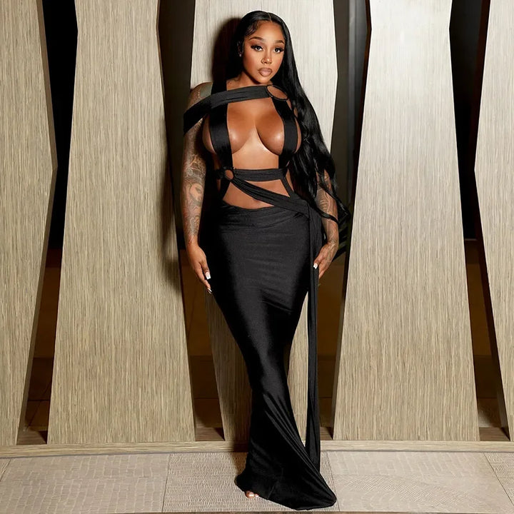 Woman wearing a black outfit with sheer elements in a room with wooden paneling.