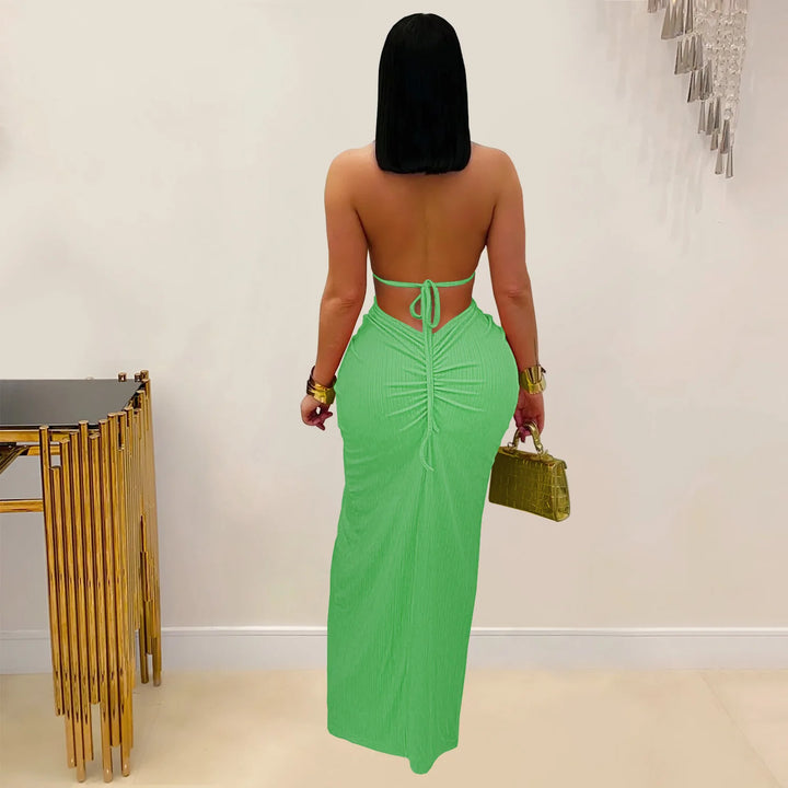 Woman in a green dress holding a handbag against a neutral background