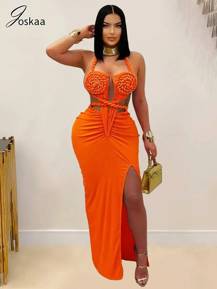 Woman wearing an orange dress with a high slit, holding a gold handbag, against a plain background.