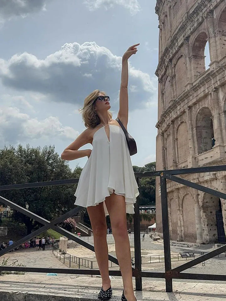 Woman in a white dress standing in front of the Colosseum in Rome.