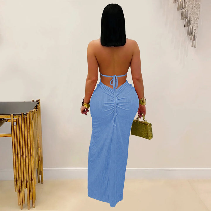 Woman wearing a blue dress with a gold handbag in an indoor setting