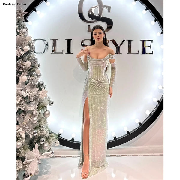 Woman in a silver evening gown posing in front of a 'Soli Style' sign with a Christmas tree on the left.
