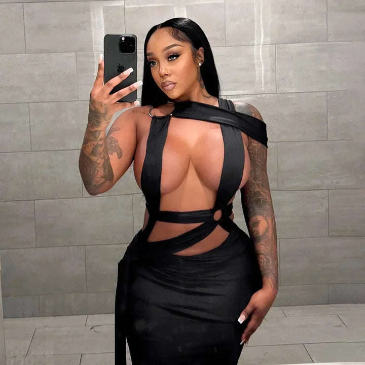Woman taking a mirror selfie wearing a black dress with cut-out design against a tiled wall.