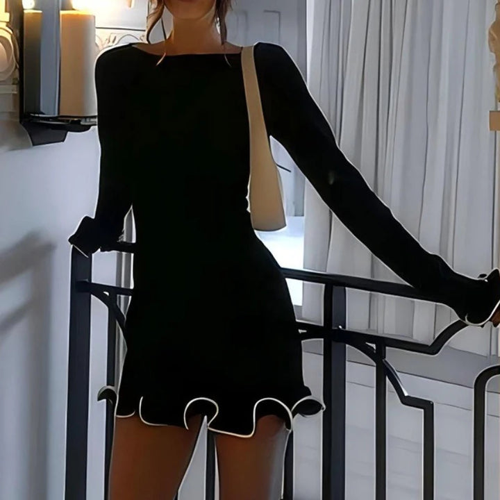 Person wearing a black dress with long sleeves in an indoor setting.
