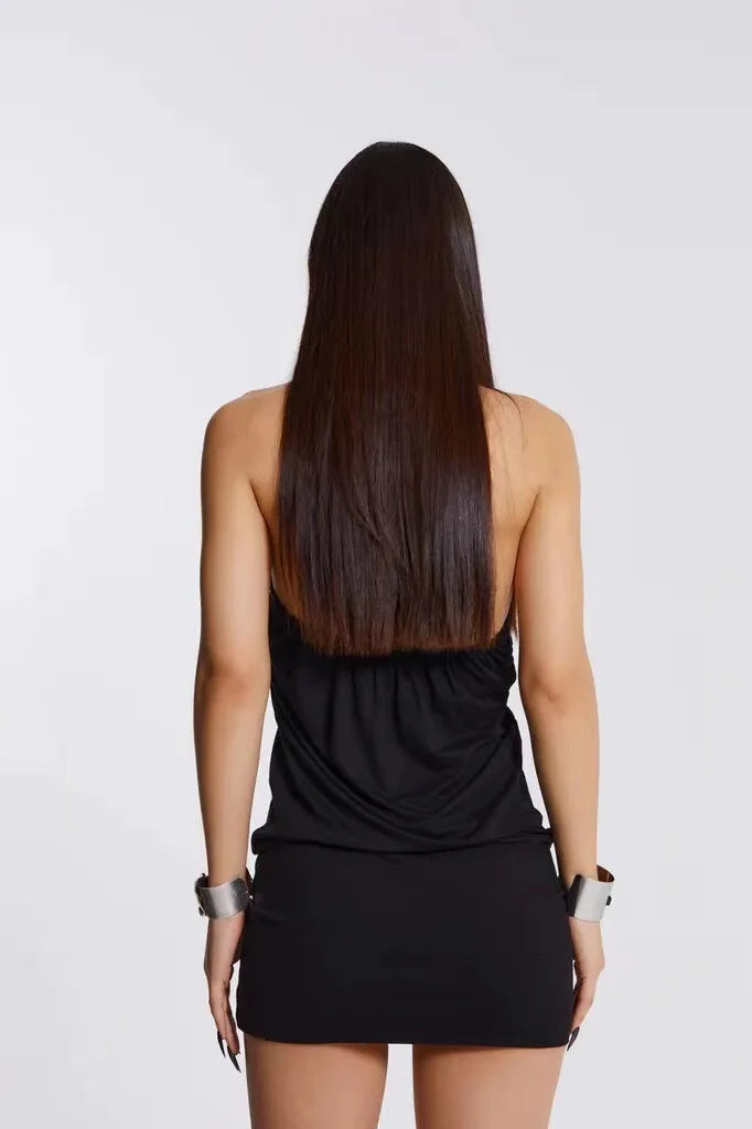 Person wearing a black sleeveless top and skirt with long hair on a white background