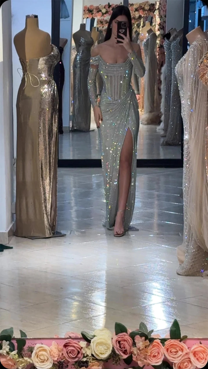 Person wearing a silver sequin dress in a fitting room with mannequins and floral decorations.