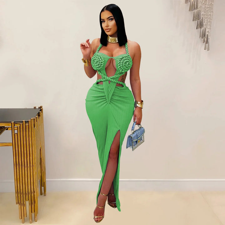 Woman wearing a green dress with a high slit, holding a blue clutch, in an indoor setting.