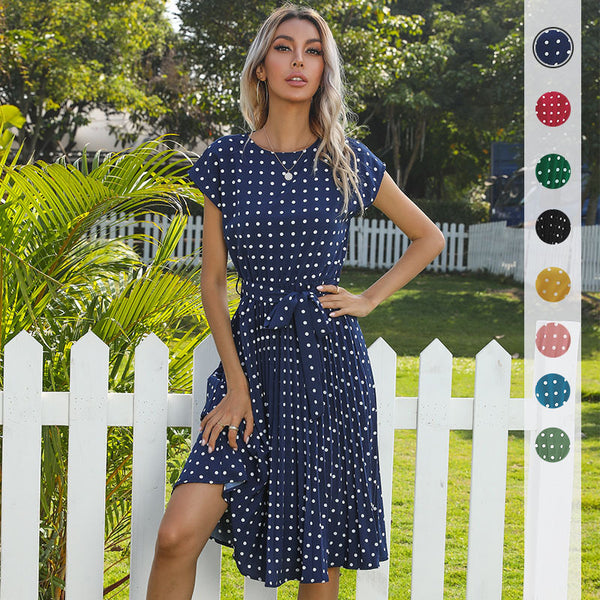 Woman in a blue polka dot dress standing in front of a white picket fence with a color swatch on the right.